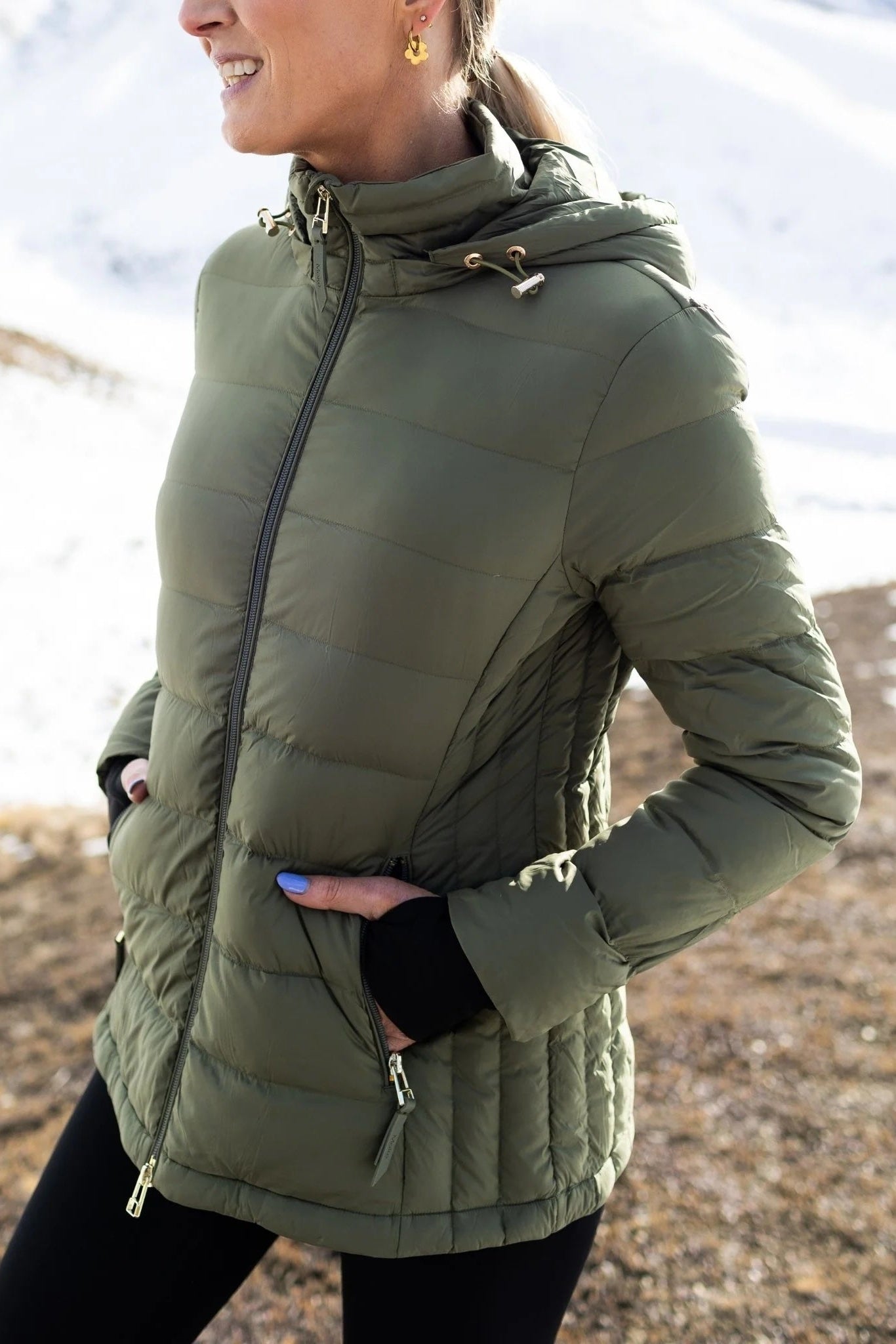 Person wearing a green puffer jacket outdoors with a blurred natural background