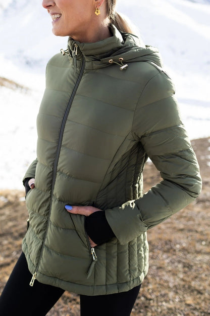 Person wearing a green puffer jacket outdoors with a blurred natural background